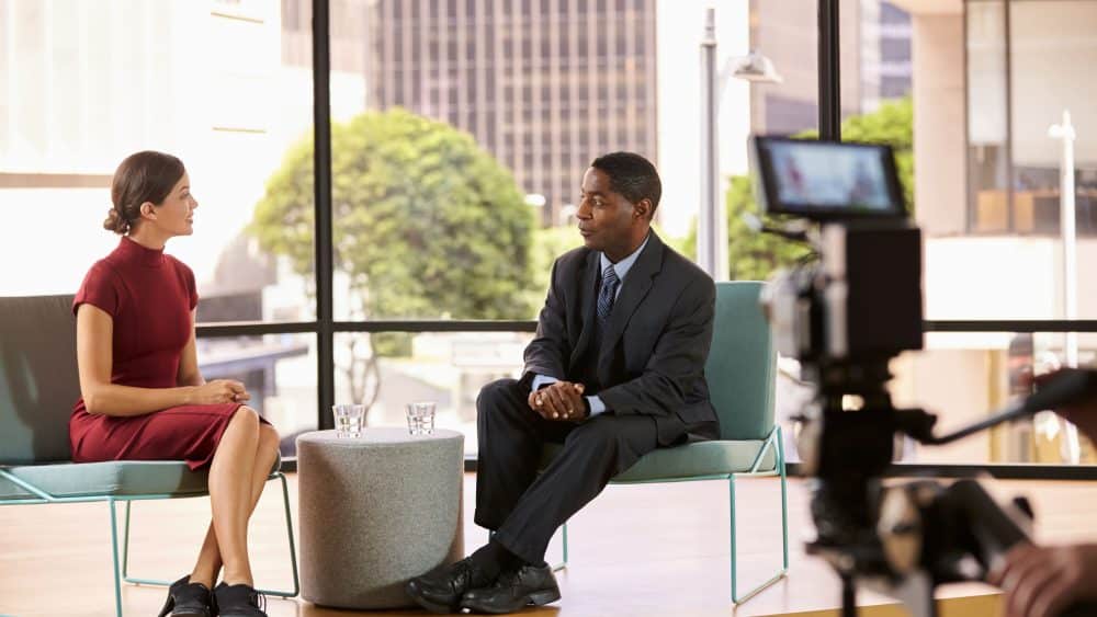 TV presenter giving training to business man on how to feel comfortable in front of a camera